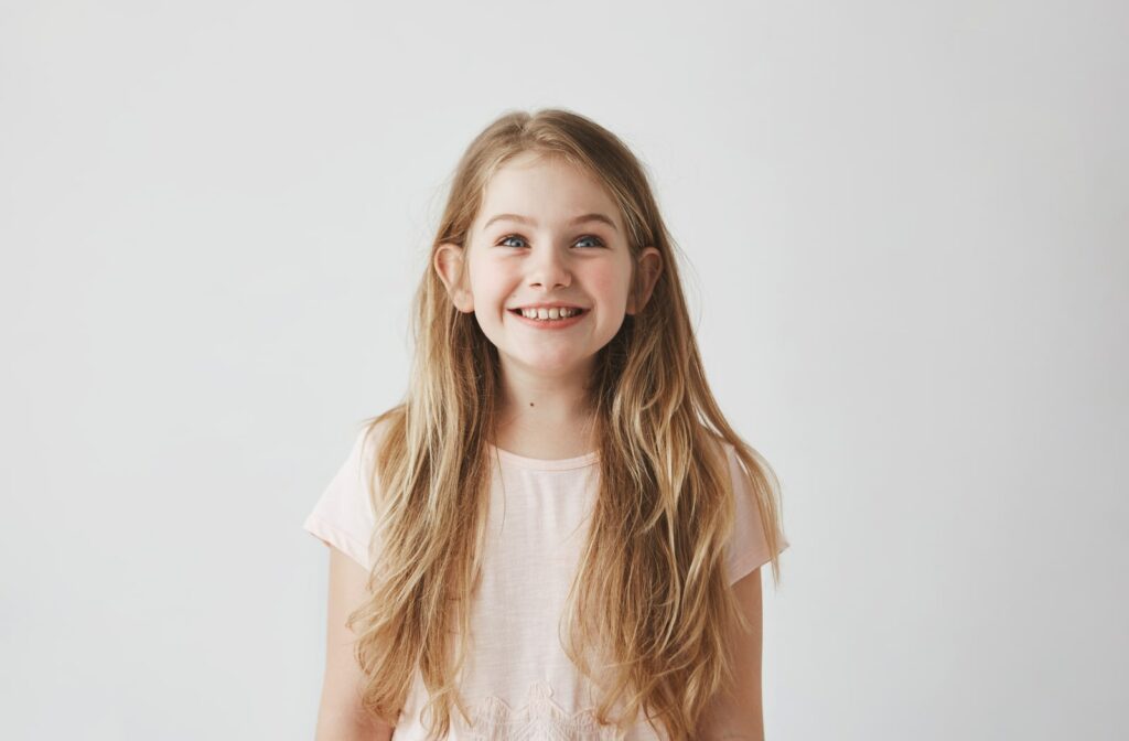 A young girl smiling and standing against a white backdrop