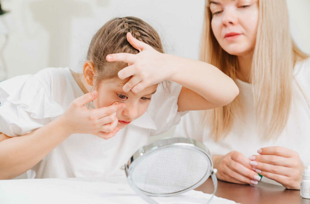 A young girl learning how to put orthokeratology contact lenses in her eye to slow the progression of myopia