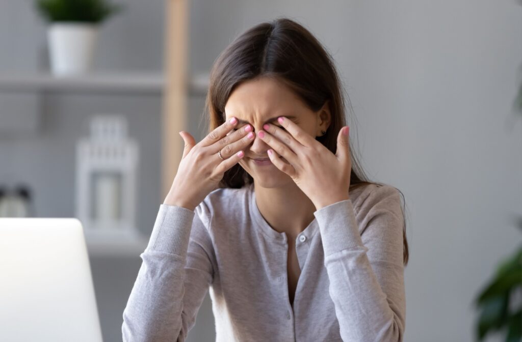 A young woman rubbing her eyes in frustration due to discomfort from blocked oil glands.