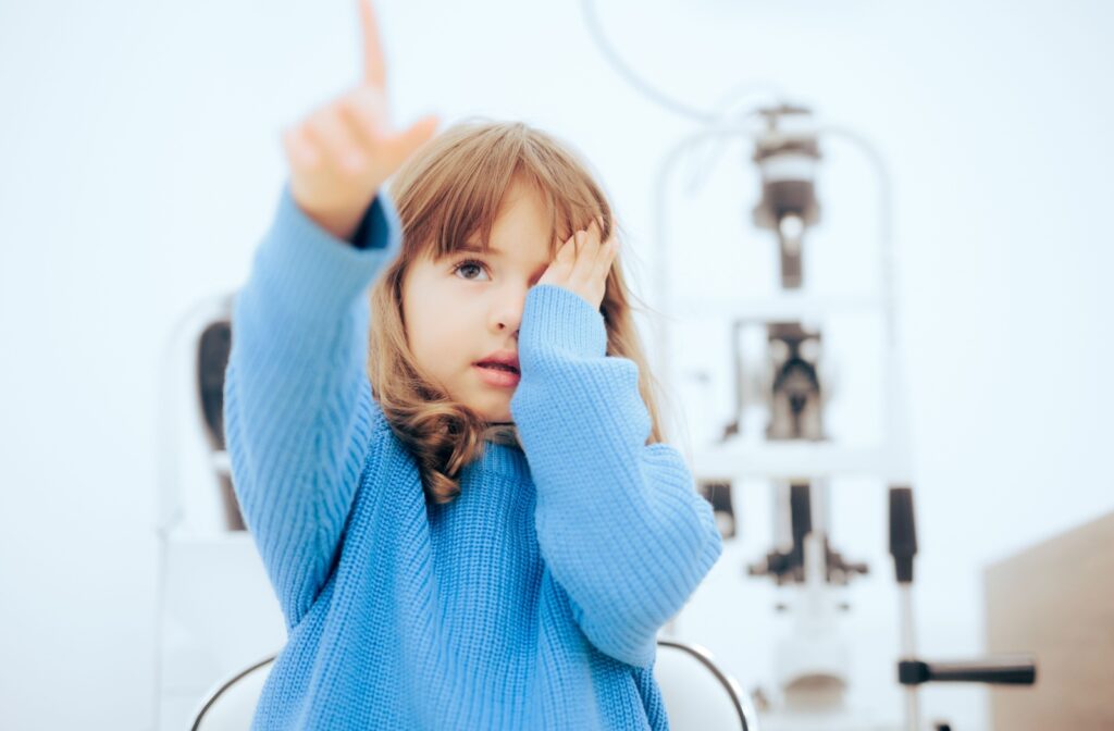 A young child at an optometrist's office covering one eye during an eye test to determine if they have myopia, also known as nearsightedness.