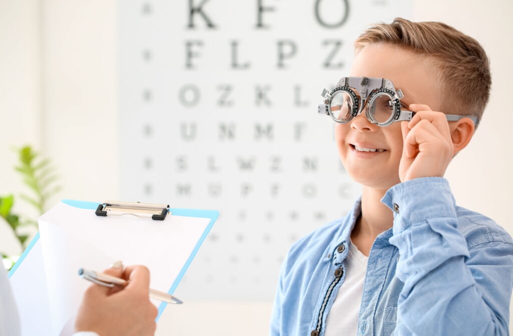 A smiling little boy wearing special glasses during an eye exam with an optometrist discussing myopia control.