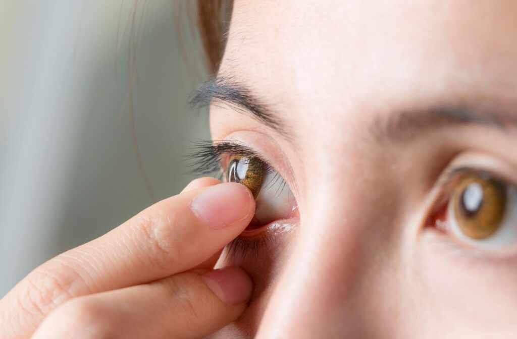 Close-up of fingers gently reaching toward the eye to remove a contact lens.